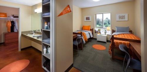 a view of a pitzer double room with two twin beds, a bathroom, closets, and storage