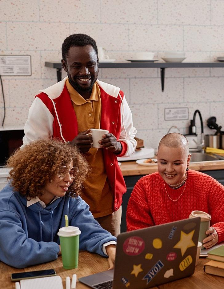 three students sit in their off-campus kitchen and chat